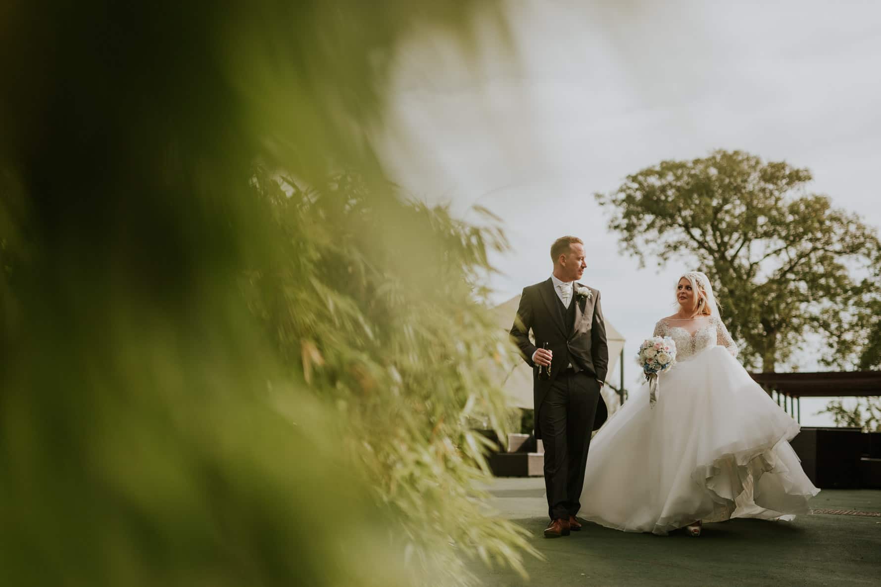 bride and groom walking near a hedge