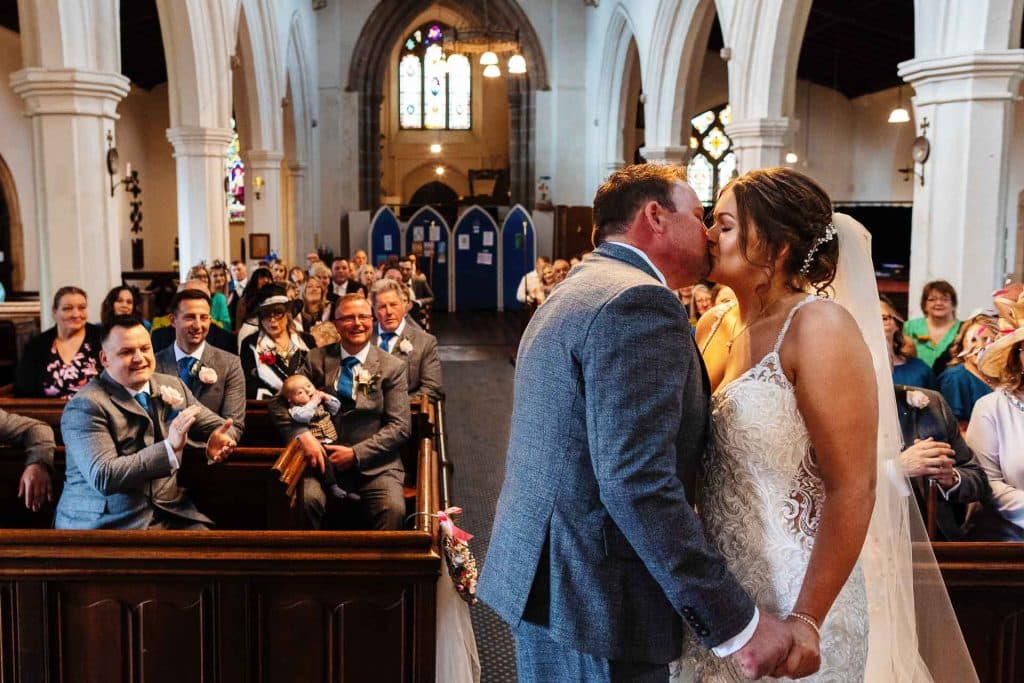 Elegant wedding ceremony inside a historic church with a bride and groom exchanging vows, surrounded by delighted guests, capturing a memorable moment of love and celebration.