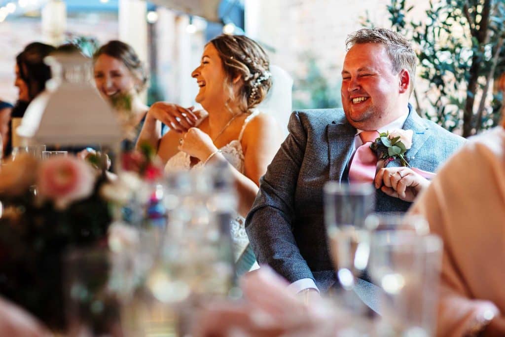 Elegant wedding reception with guests laughing and enjoying a special moment at BGS Weddings in the UK, celebrating love and happiness with stunning decor and joyful atmosphere.