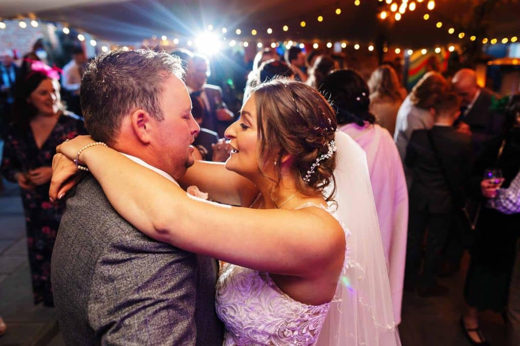 Elegant couple dancing at wedding reception with warm ambient lighting, celebrating love and marriage, captured by BGS Weddings, specialising in dream wedding photography and videography services in the UK.