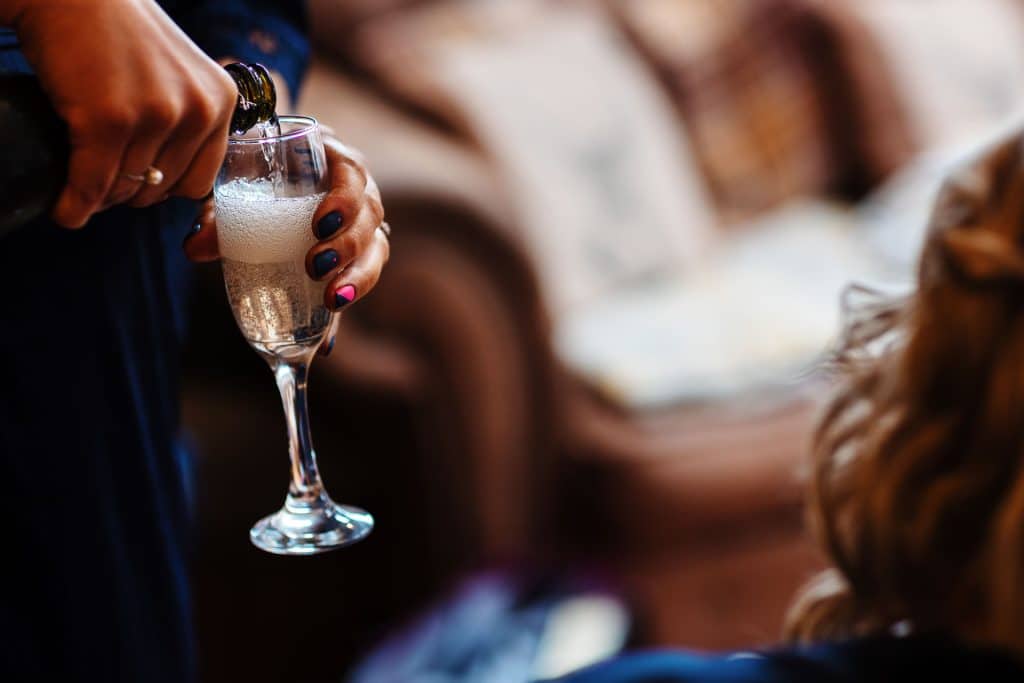 Champagne being poured into a flute at a wedding celebration, capturing the joyful and celebratory atmosphere.