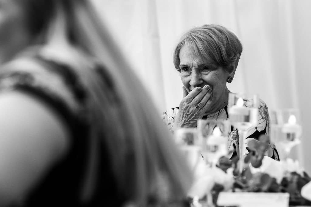 Elegant elderly woman laughing at a wedding reception, capturing joyful moments and happy emotions at BGS Weddings, a premier wedding venue in the UK.
