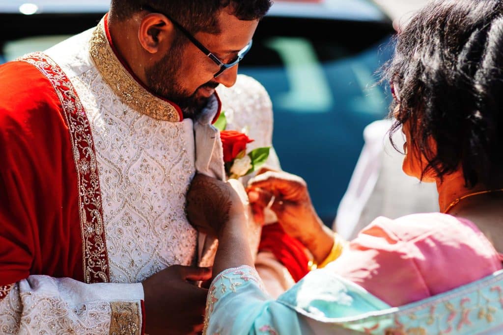 Traditional Indian wedding ceremony with groom in ornate sherwani and bride's family, vibrant colours, cultural rituals, celebrating love and heritage.