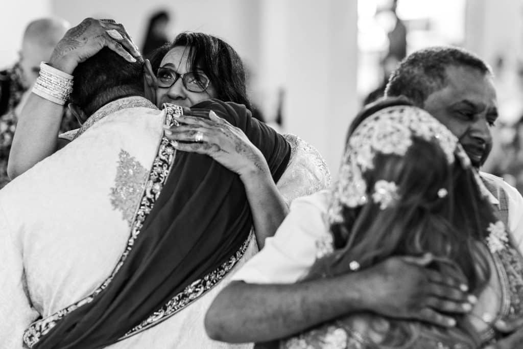 Emotional wedding embrace capturing diverse couples, heartfelt moments of love, joy and connection during a multicultural wedding celebration, with elegant attire and traditional details.