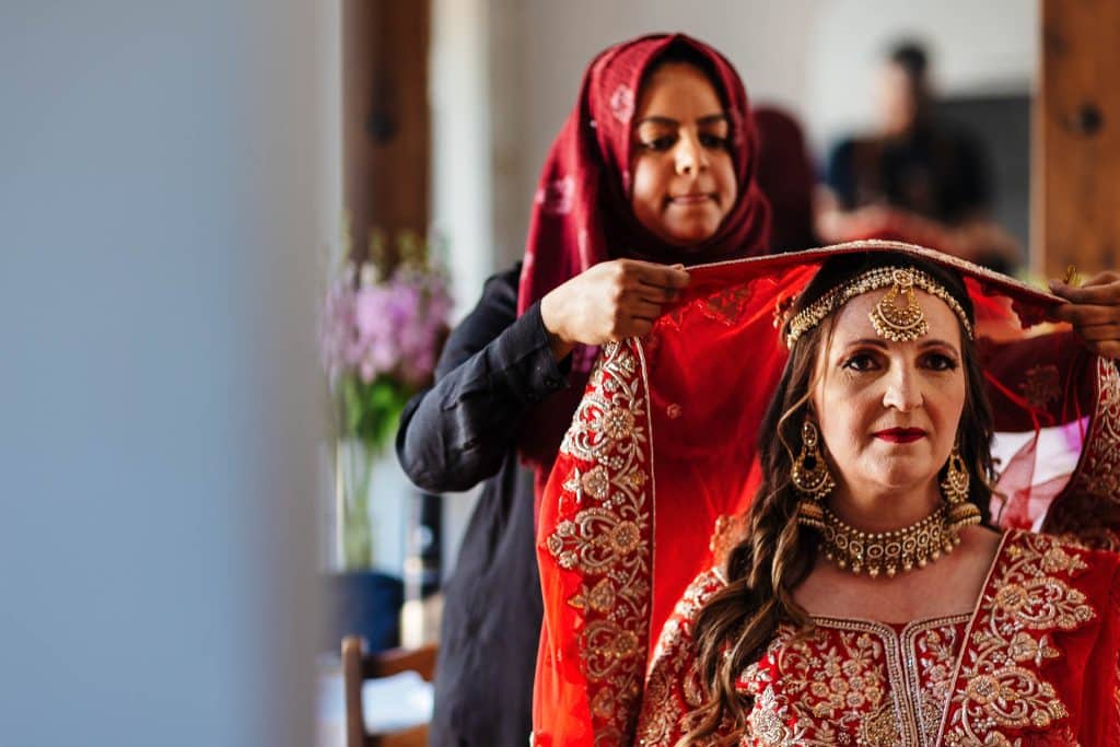 Elegant bridal jewellery being adjusted by a woman wearing traditional South Asian attire at a wedding.