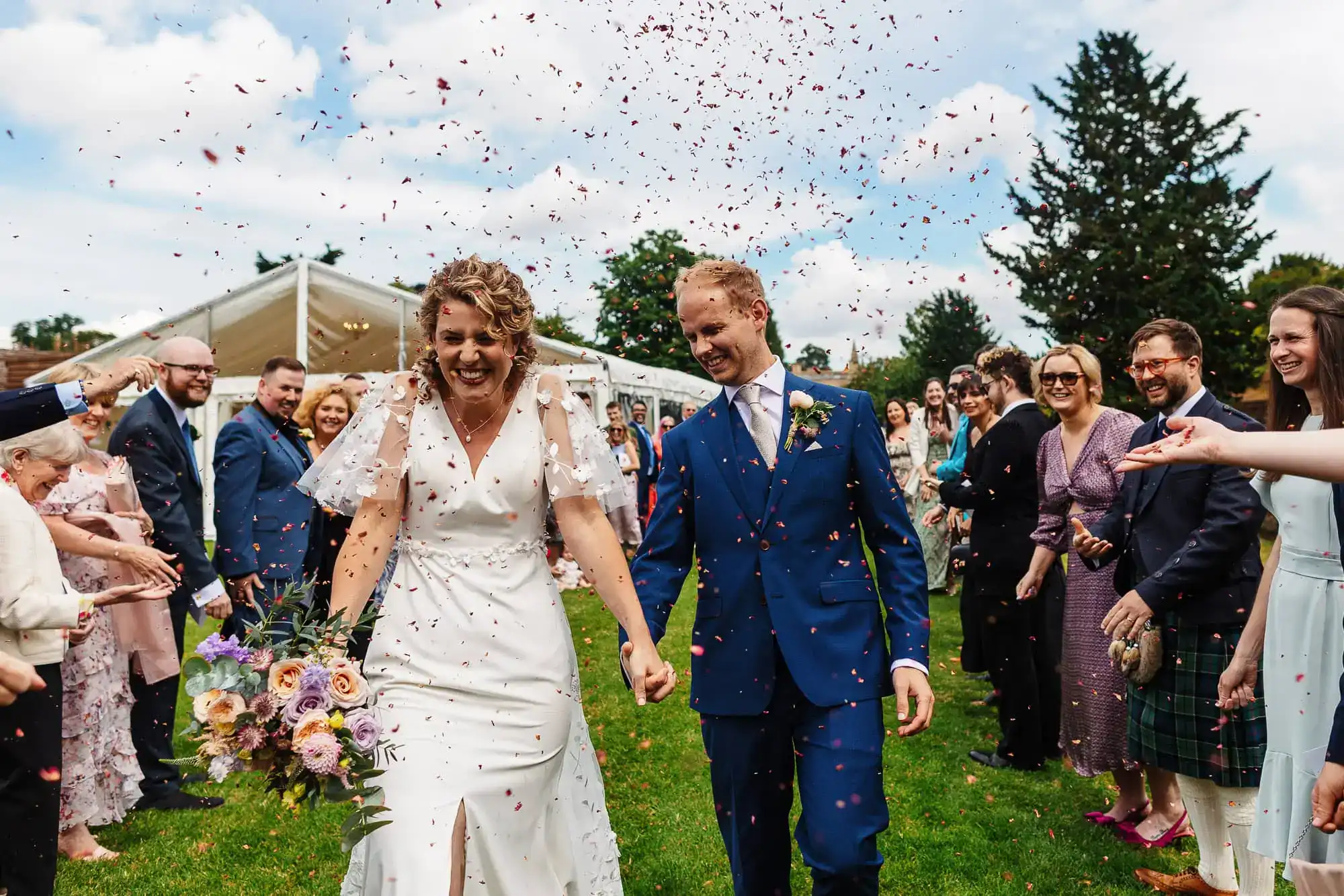 Elegant wedding photoshoot at BGS Weddings, showcasing the bride and groom celebrating with family and friends during a joyful outdoor wedding ceremony in the UK.