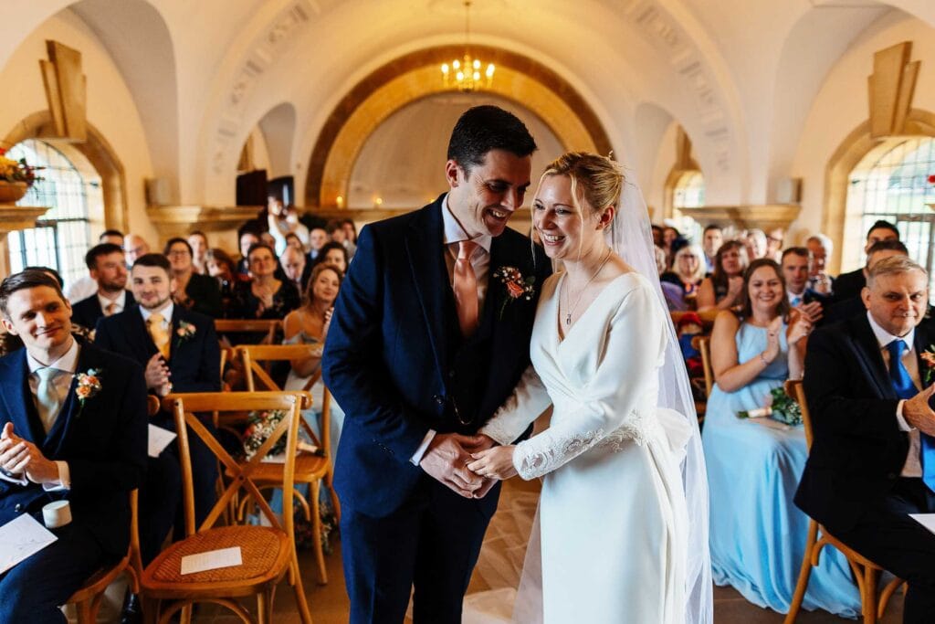 Elegant wedding ceremony at BGS Weddings with bride and groom exchanging vows in a historic church setting, surrounded by joyful guests and beautiful architecture.