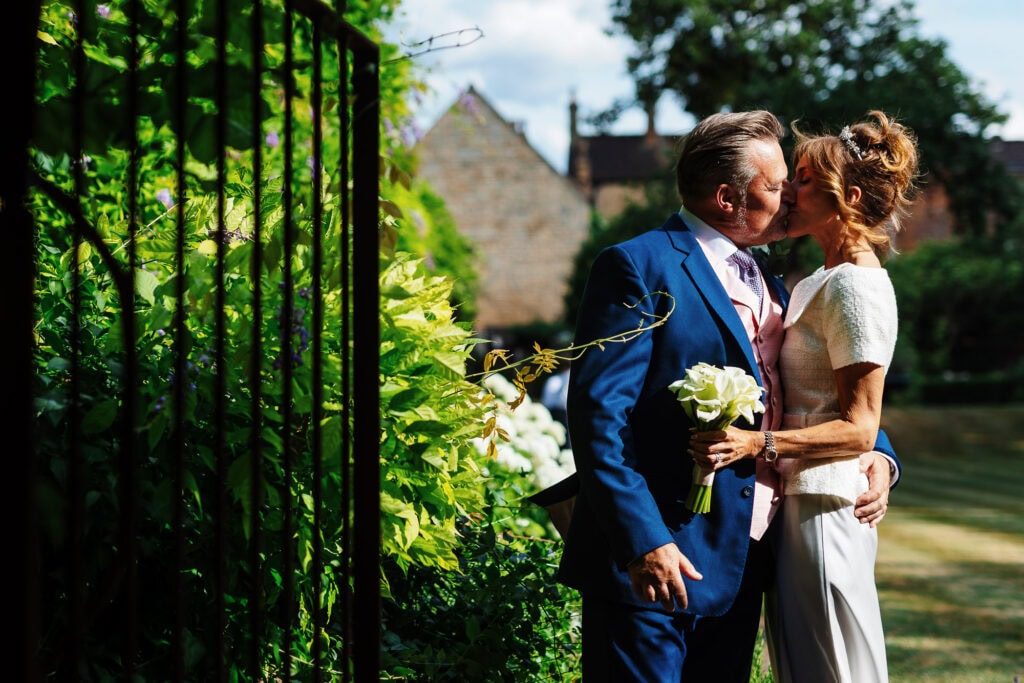 Elegant wedding couple sharing a kiss outdoors in lush garden setting for BGS Weddings.