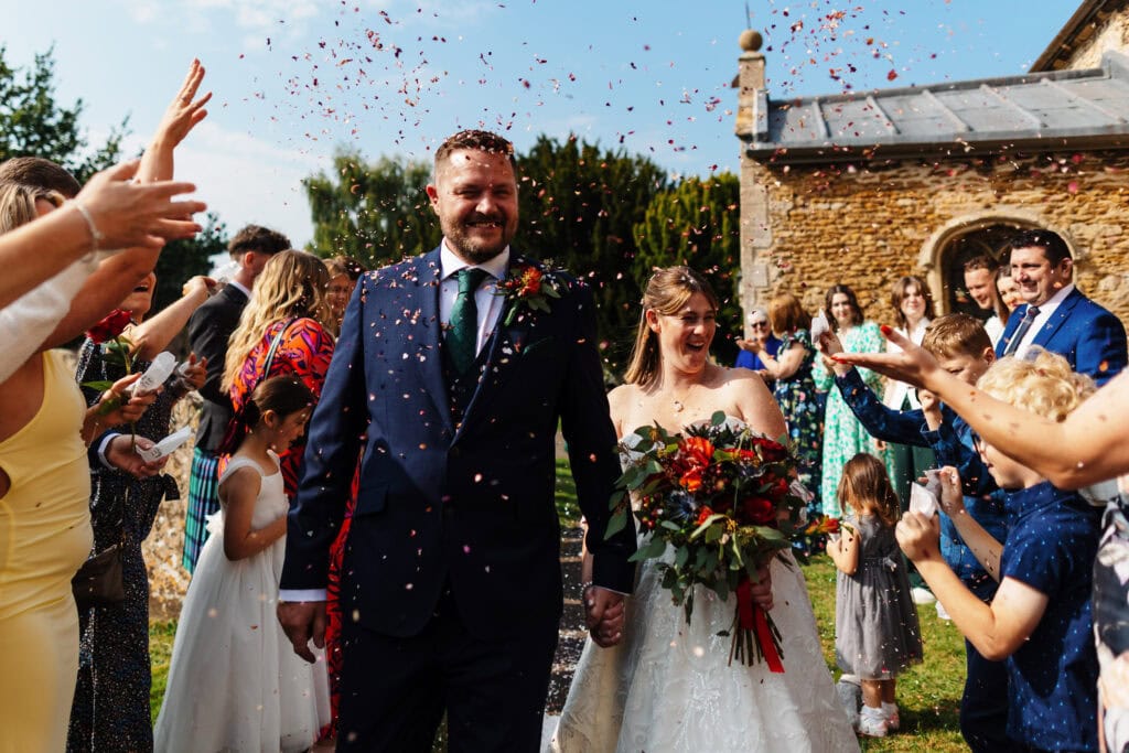 Celebrate wedding joy with BGS Weddings: happy bride and groom surrounded by friends and family, confetti in the air during a beautiful outdoor ceremony. Perfect for creating unforgettable wedding memories.