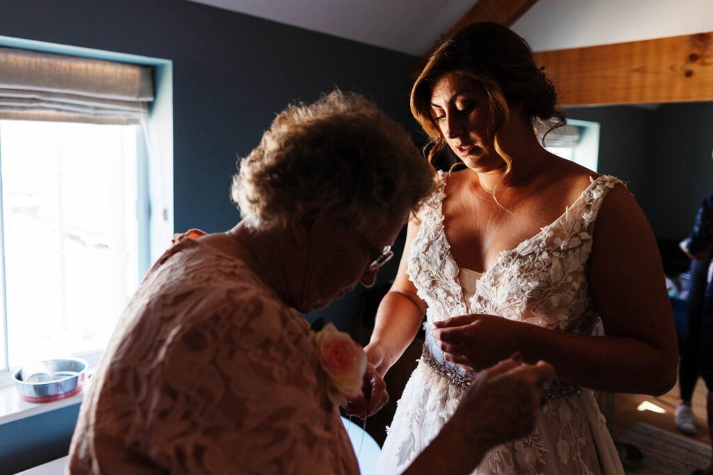 Elegant bride getting ready with her mother in a cosy, beautifully lit wedding preparation room, capturing special moments before the wedding ceremony for BGS Weddings.