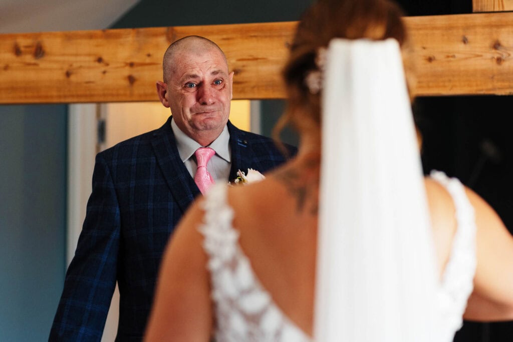 Emotionally touching moment of a father seeing his bride in her wedding dress, captured during a wedding preparation at BGS Weddings.