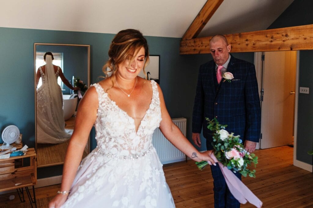 Beautiful bride with bouquet in a wedding dress, indoors with a wooden ceiling beam, preparing for her wedding at BGS Weddings, creating unforgettable wedding memories.