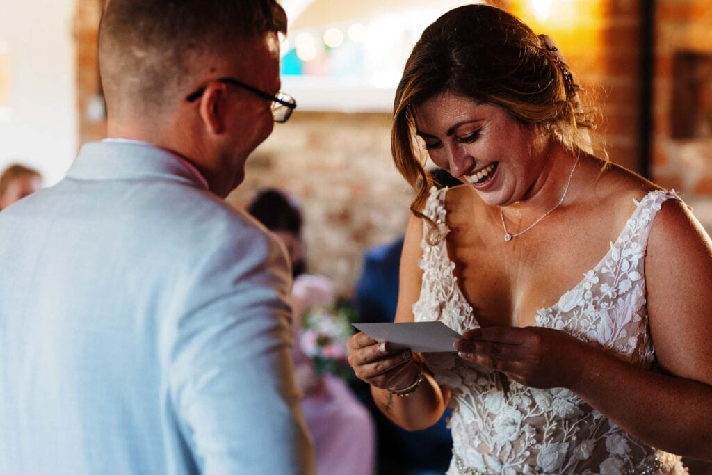 Elegant bride reading a heartfelt letter during her wedding reception at BGS Weddings in the UK, celebrating love and marriage.
