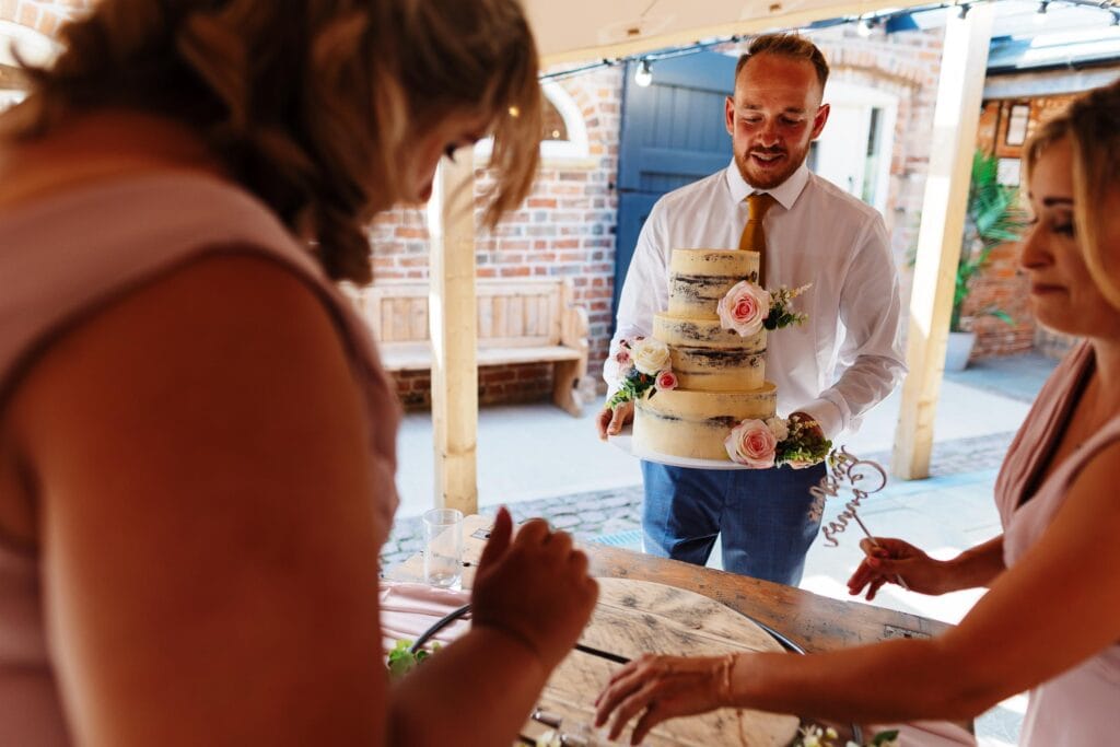 Elegant wedding cake with fresh pink roses at BGS Weddings, showcasing beautiful wedding celebration details.