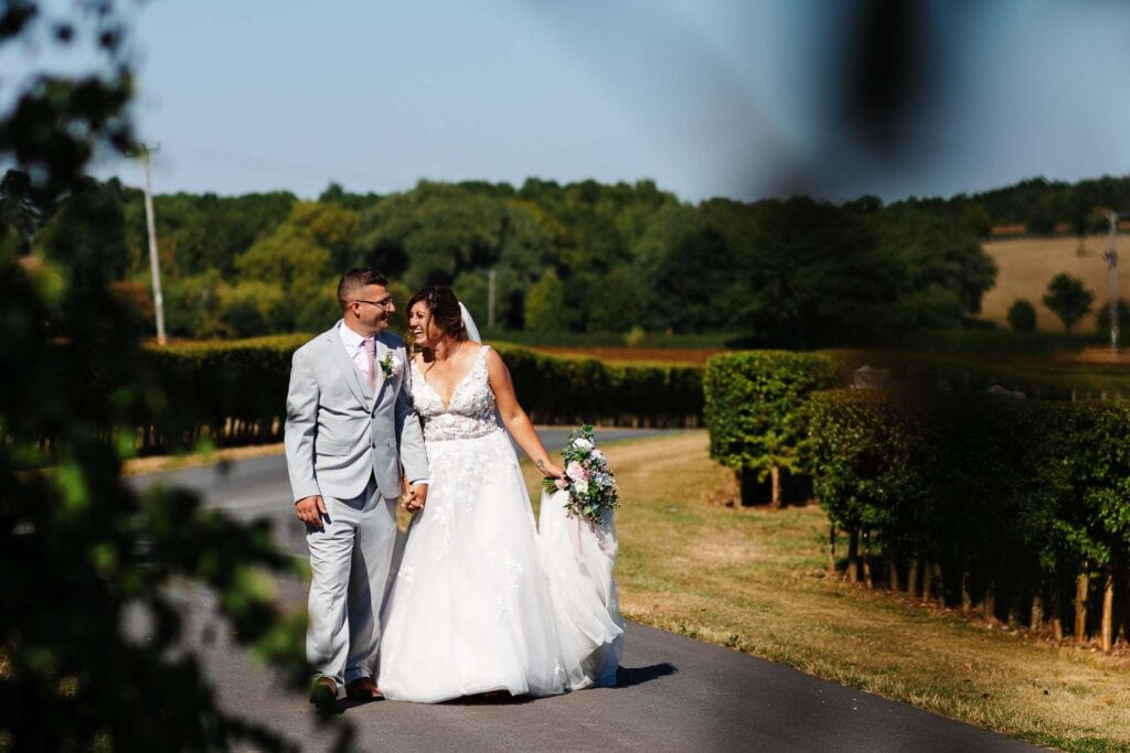 Elegant wedding couple walking hand in hand through a lush countryside setting, capturing the romance and joy of a wedding day at BGS Weddings.