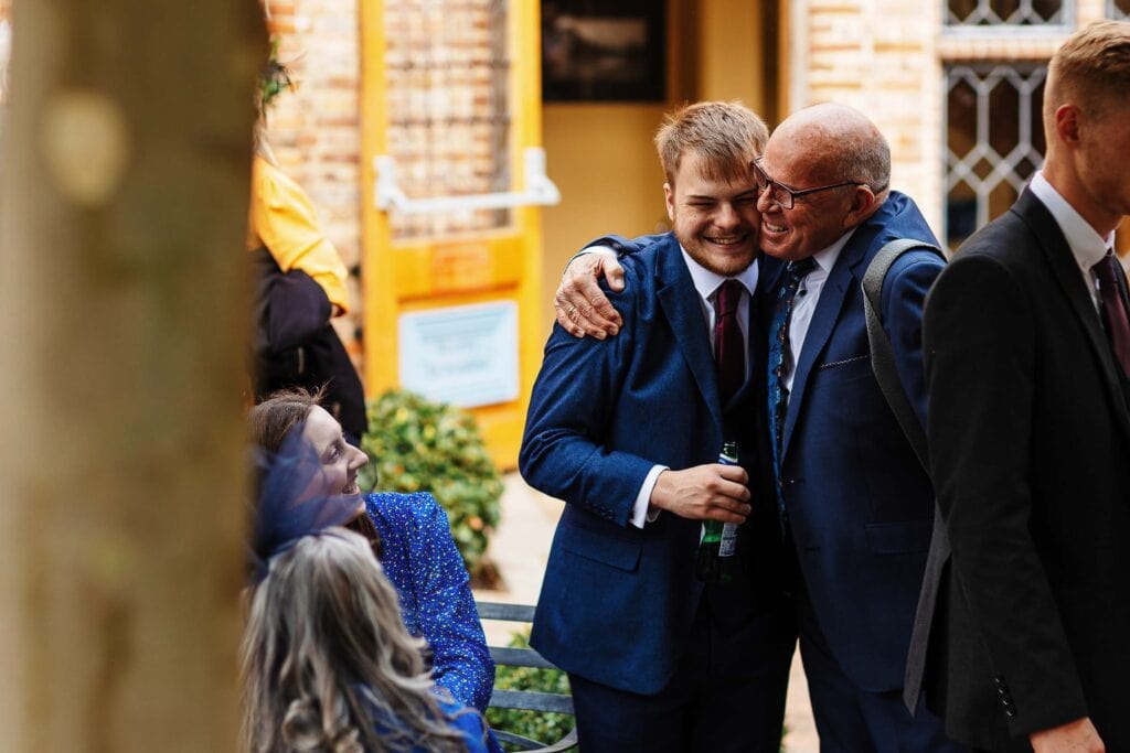 Cheerful wedding guests celebrating outdoors at BGS Weddings, joyful embraces, happy moments, wedding reception, friends and family gathering, outdoor wedding venue, celebration, happiness, wedding party.
