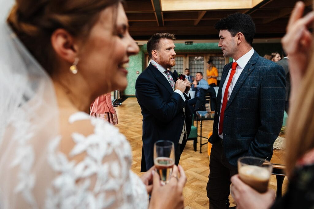 Elegant wedding reception with guests enjoying drinks, featuring bride and groom, stylish attire, and lively atmosphere at BGS Weddings.