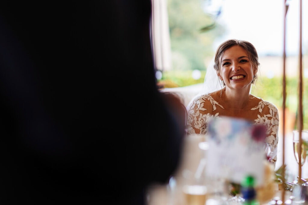 Elegant bride smiling during wedding reception at BGS Weddings, showcasing beautiful wedding dress and joyful atmosphere.