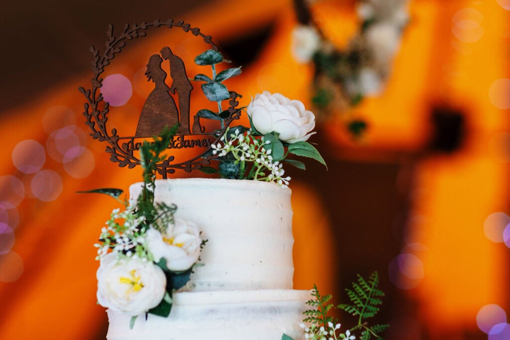 Elegant wedding cake with white floral decorations and a personalized cake topper featuring a silhouette of a bride and groom; perfect for wedding celebrations.