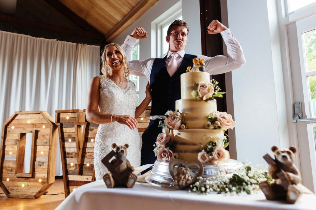 Elegant wedding cake at brooksby hall wedding photographer with fresh roses and floral decorations at BGS Weddings, showcasing memorable bridal moments and sophisticated wedding celebration arrangements.