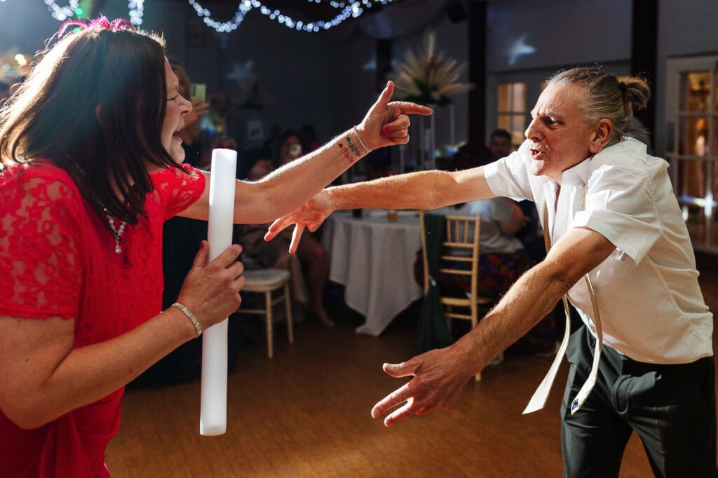 Joyful wedding dance moment with a woman in a red dress and a man in a white shirt celebrating at BGS Weddings in the UK.