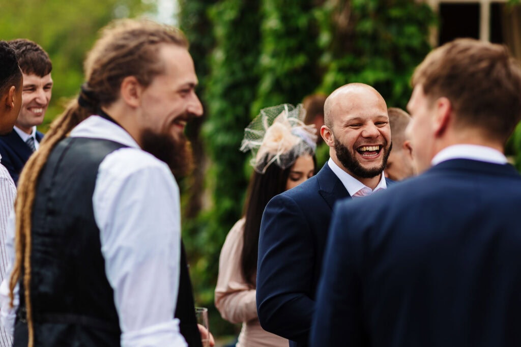 Laughter and joy among wedding guests at an outdoor BGS Weddings event, capturing the celebration and happiness of a wedding day in a lush garden setting.