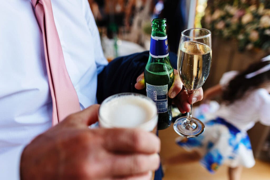 Celebration at wedding reception, guests enjoying drinks, champagne, beer, and beer poured in glasses, joyous atmosphere, wedding day festivities, BGS Weddings, elegant event setup, bride and groom celebration, romantic occasion.