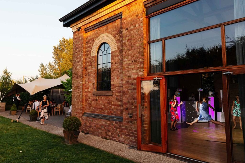 Elegant brick wedding venue with outdoor dining area and indoor dance floor, perfect for wedding celebrations and receptions.