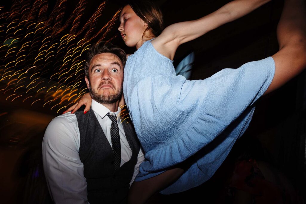 Energetic wedding dance photo featuring a groom and bride in a lively celebration setting, capturing dynamic movement and joyful atmosphere at a wedding in the UK.