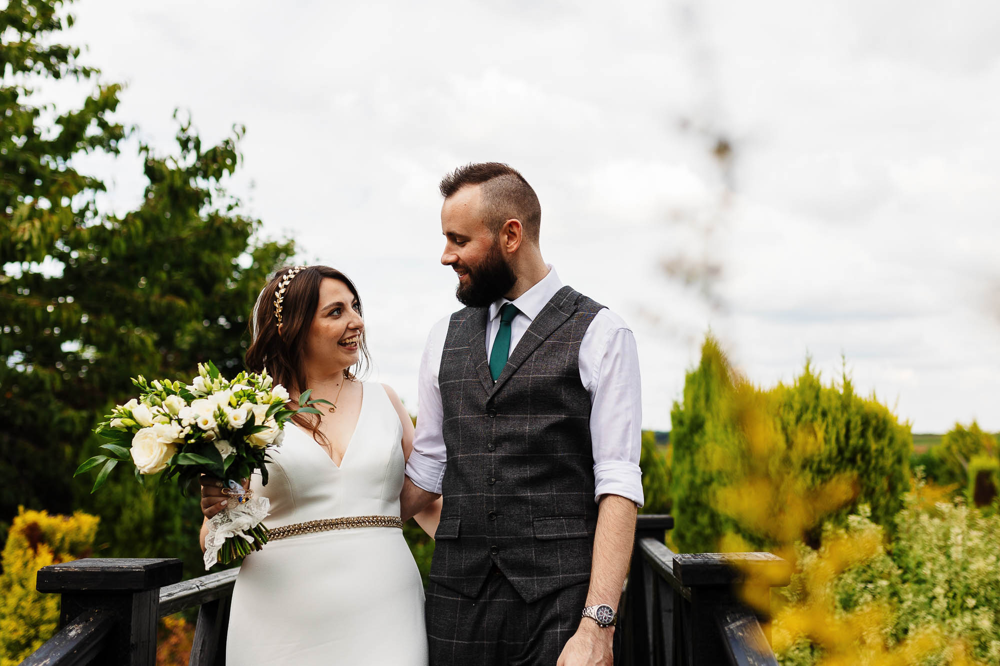 Elegant bride and groom during outdoor wedding photoshoot, capturing their happy moment on a scenic garden terrace with lush greenery.