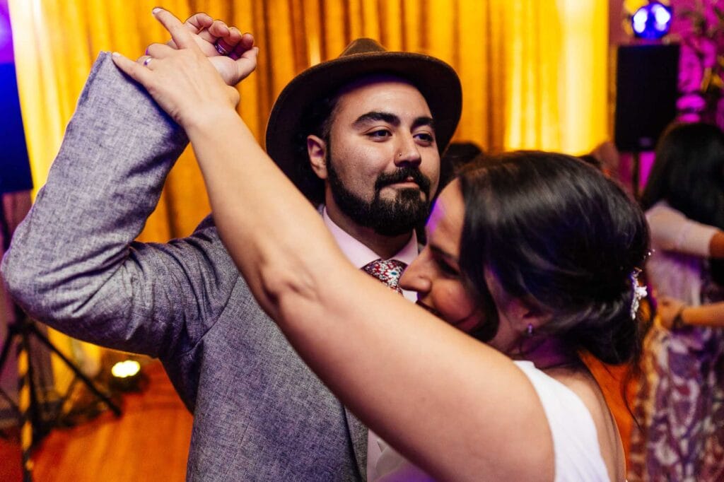 Elegant wedding couple dancing at BGS Weddings, capturing a joyful moment with vibrant lighting and celebration atmosphere.