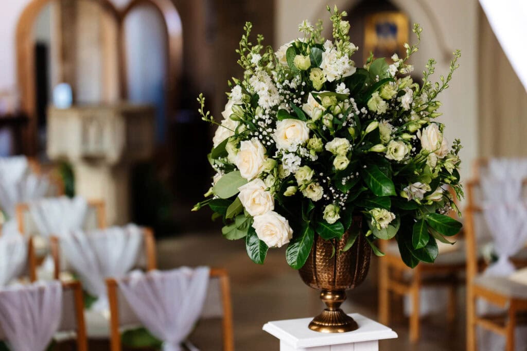 Elegant floral wedding centrepiece with white roses and greenery, designed for a sophisticated wedding reception at BGS Weddings.