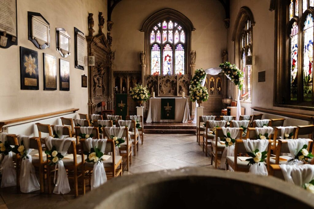 Elegant church wedding ceremony setup with floral decorations and stained glass windows, perfect for romantic wedding venues from BGS Weddings.