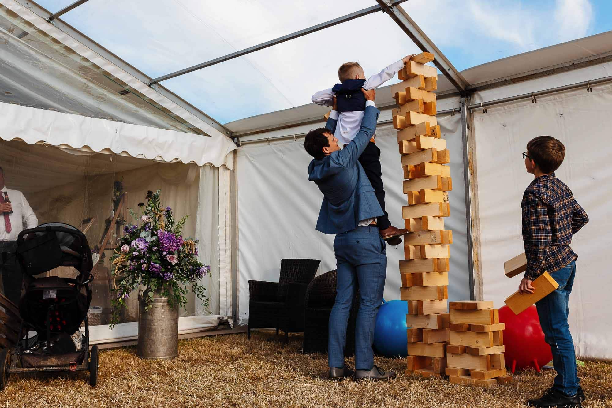 Wooden Jenga game at a wedding reception, bringing fun and entertainment to guests, with a family enjoying the game inside a marquee.