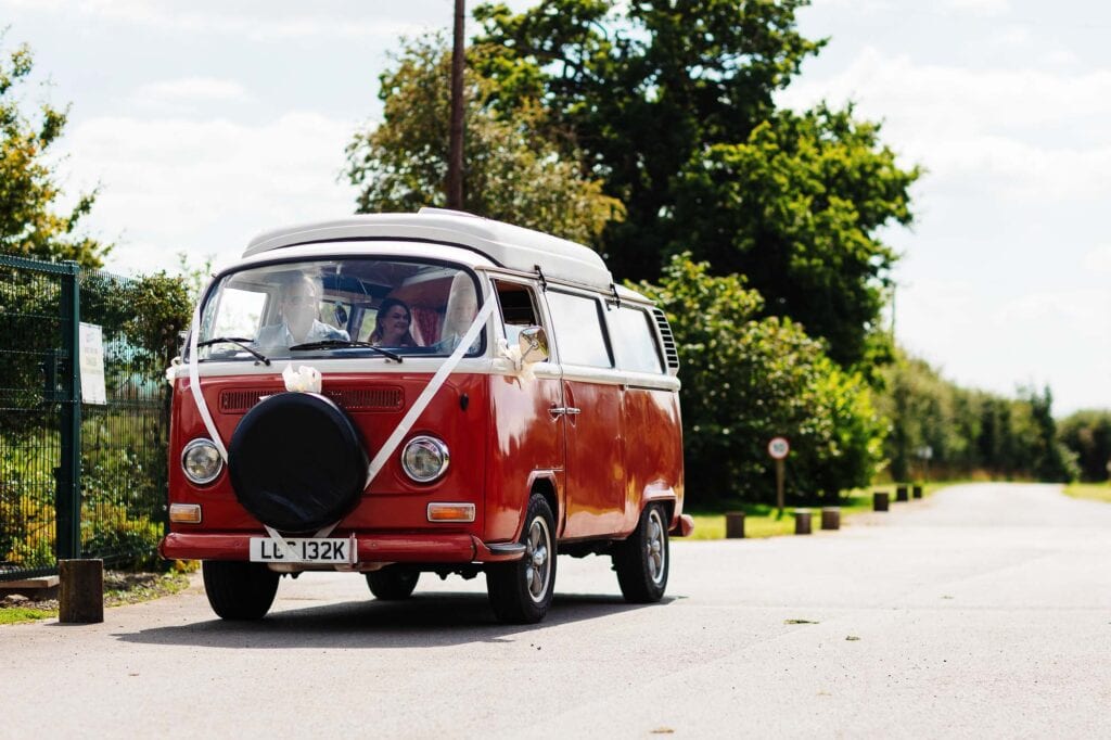 Vintage red Volkswagen camper van decorated for wedding, perfect for wedding transportation and photo backdrop.