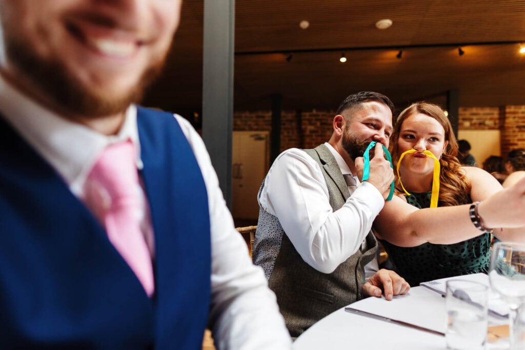 Smiling wedding guests having fun at BGS Weddings reception, celebrating with colourful ribbons, joyful atmosphere, wedding entertainment in the UK, lively wedding event, happy couple celebration, wedding photography, BGS Weddings venue relevance.