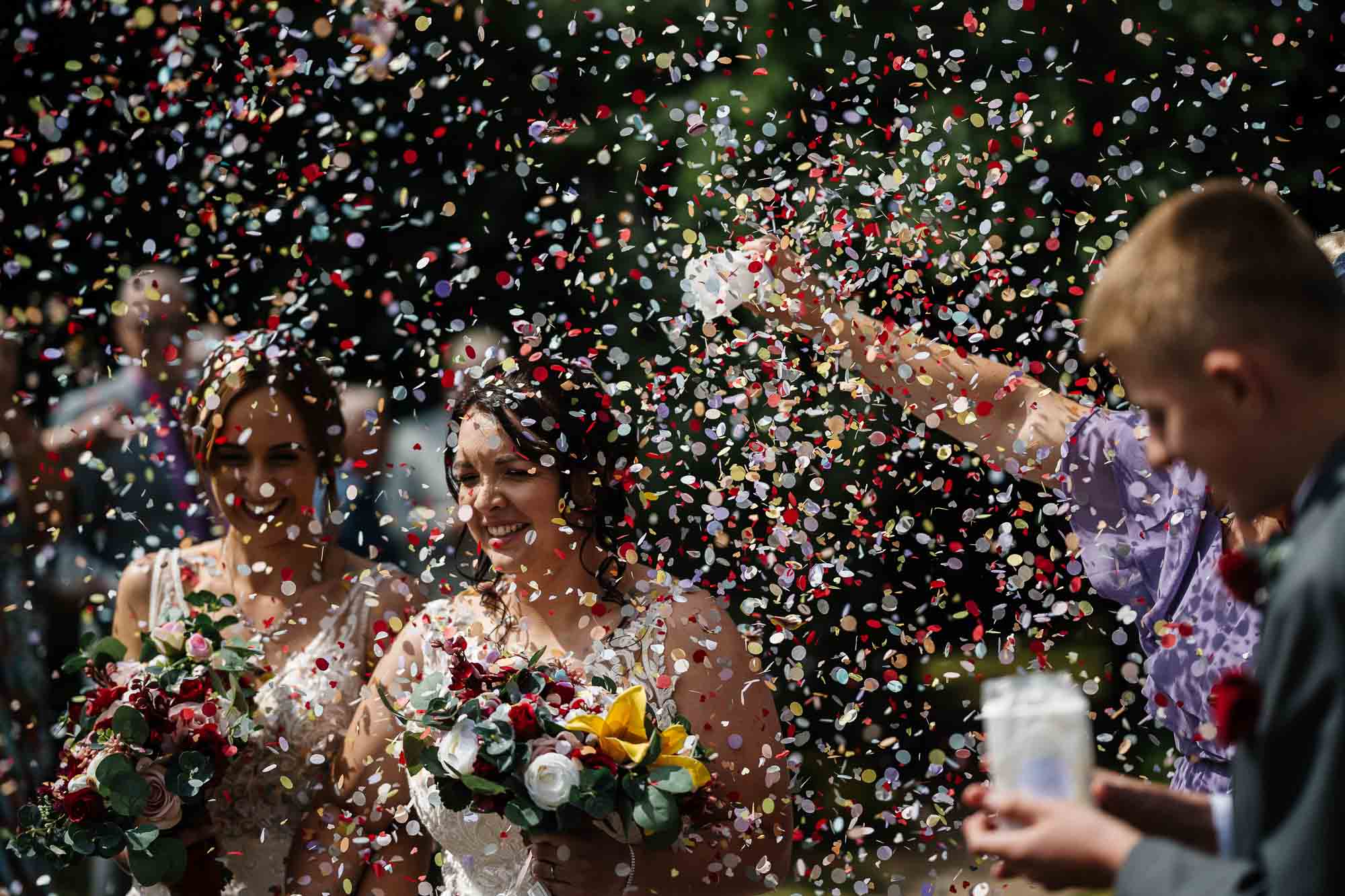 Shearsby bath wedding photographer Confetti celebration at wedding, bride and guests under shower of colourful confetti, outdoor wedding reception, joyful moments, wedding day happiness, BGS Weddings UK.