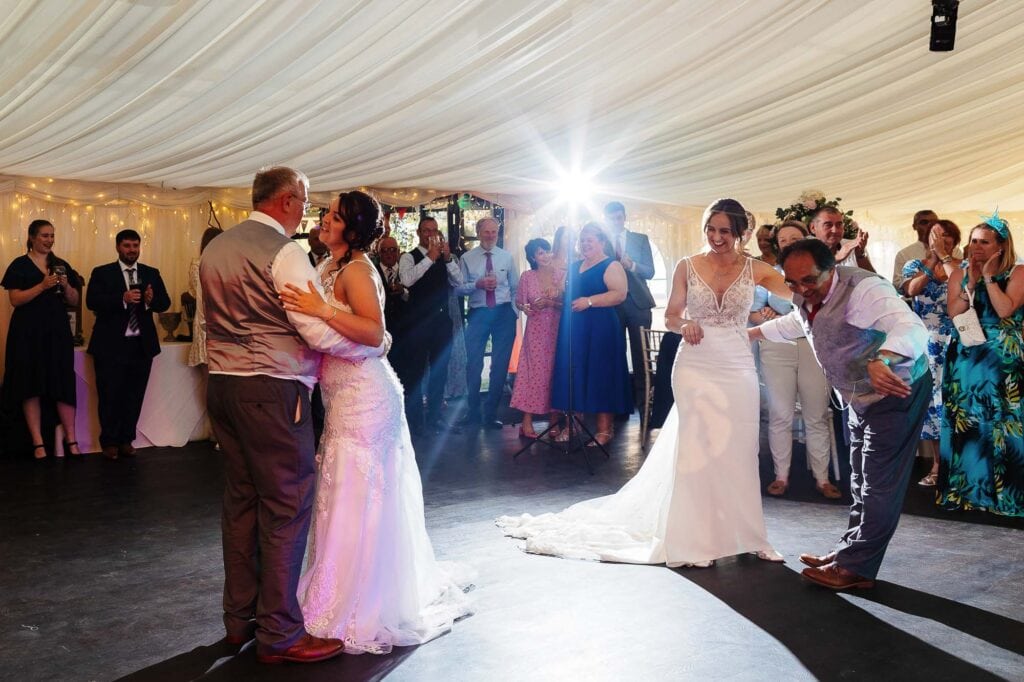 Elegant wedding dance under a large white marquee with happy guests, romantic lighting, and a joyful atmosphere at BGS Weddings.