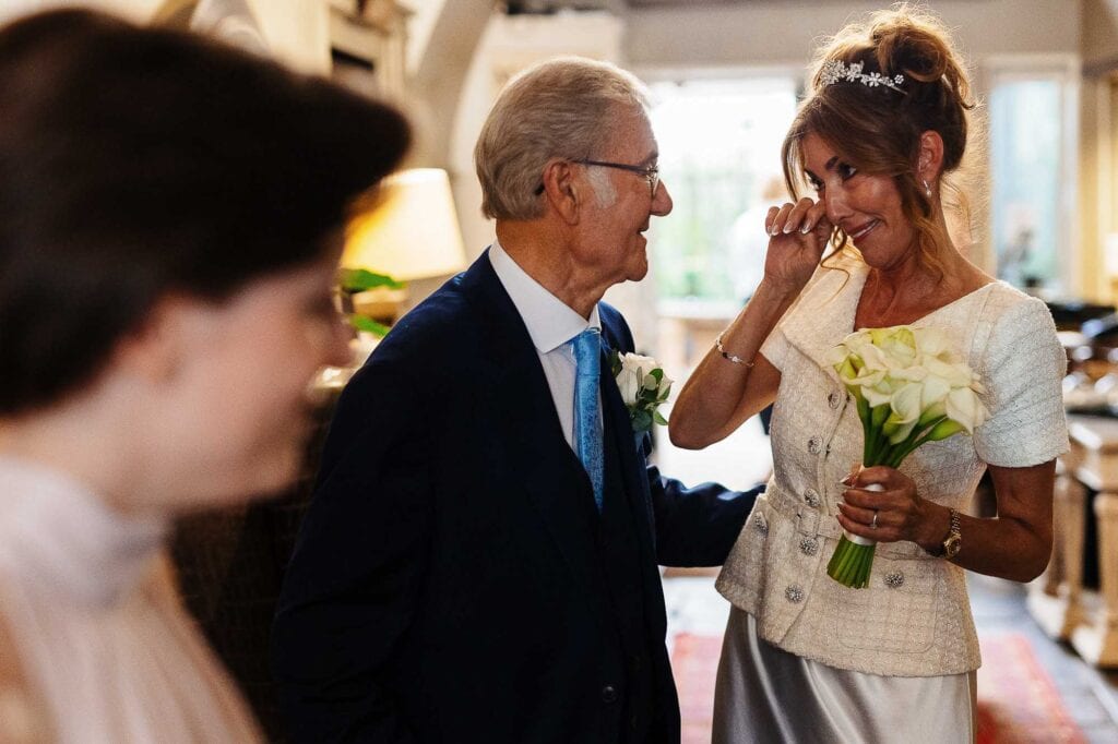 Joyful wedding moment with bride holding bouquet, emotional tears, or laughter, indoor setting, BGS Weddings, loving atmosphere, authentic love, wedding celebration, happy couple, heartfelt embrace, wedding day happiness, emotional bride.