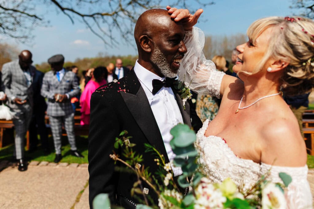 Elegant wedding couple sharing a joyful moment outdoors, with guests in the background, celebrating love and marriage at a beautiful UK wedding venue, capturing timeless wedding photography.