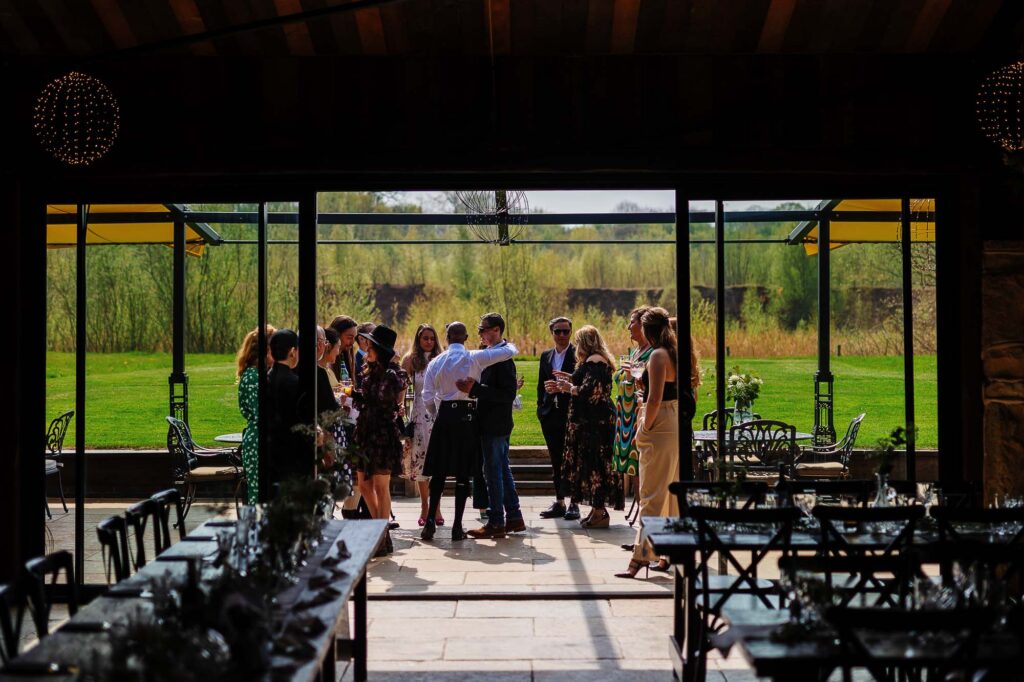 Elegant wedding reception at BGS Weddings venue with guests socialising outdoors, surrounded by lush greenery and scenic rural landscape, perfect for a memorable celebration.