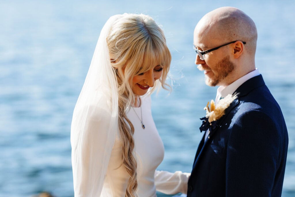 Bride and groom sharing a special moment outdoors near the water, capturing the joy and romance of their wedding day.