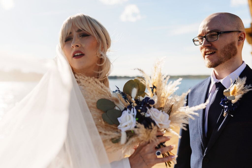 Happy bride and groom outdoors during sunset, celebrating their wedding with a beautiful bouquet and joyful expressions. Perfect for wedding photography and special day memories.