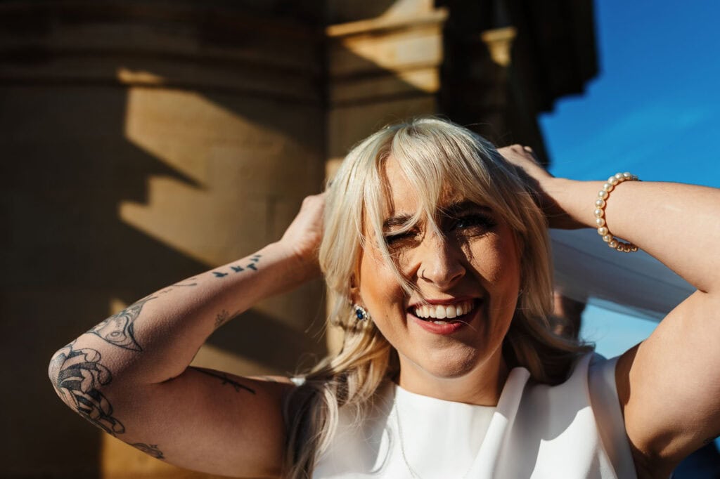 Bride smiling with hands in hair, showcasing happiness and confidence.