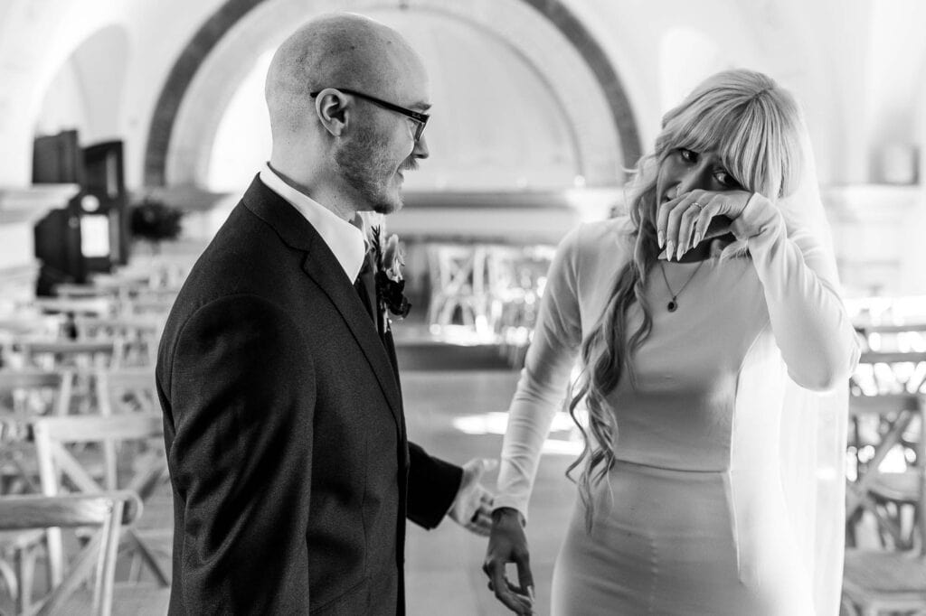 Bride and groom holding hands, with the bride visibly emotional, capturing a heartfelt moment during their wedding celebration.