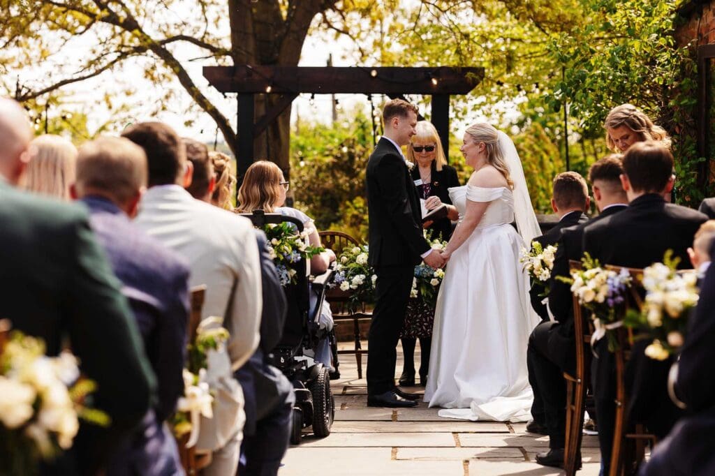 Beautiful outdoor wedding ceremony with bride and groom exchanging vows in a scenic garden setting, surrounded by friends and family.