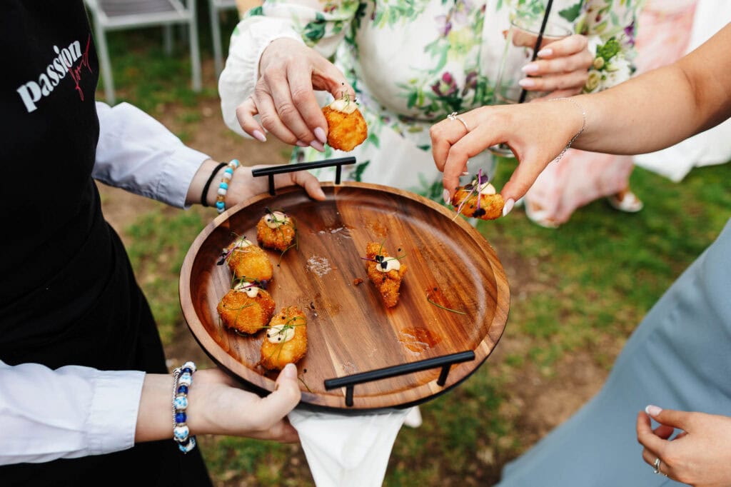 Delicious canapé appetizers served at a wedding reception, with guests enjoying finger foods outdoors.