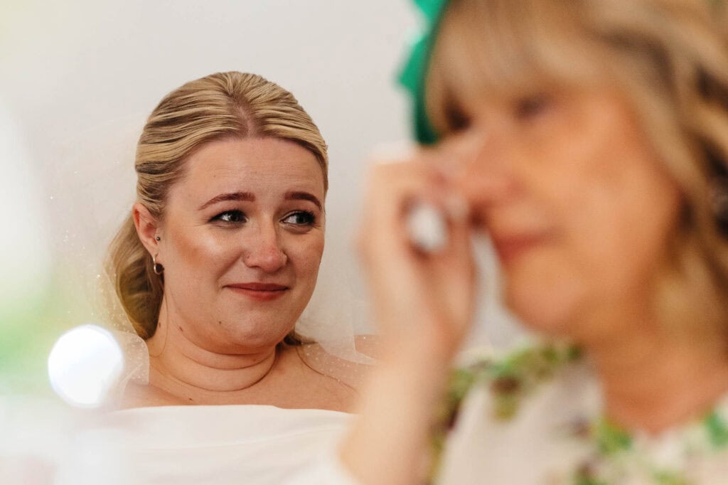 Emotional bride's reaction during her wedding ceremony, capturing a heartfelt moment with a close-up of her face and tears of joy, in a bright, elegant setting.