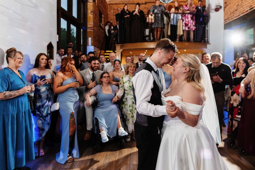 Elegant wedding dance scene with bride and groom sharing a special moment surrounded by guests at BGS Weddings venue in the UK.