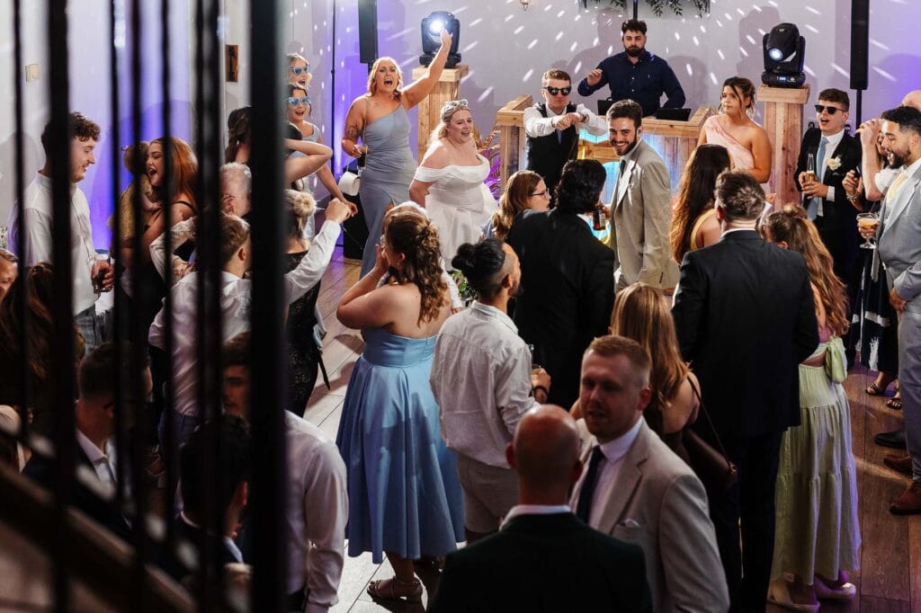 Celebration at a wedding reception with guests dancing and enjoying the party, featuring elegant attire and lively atmosphere.